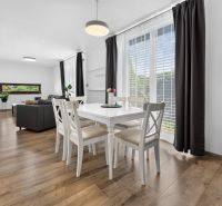 Bright living room and dining area with wood-patterned flooring in a family house.