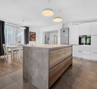 A kitchen in a family house with a kitchen island and a floor with a wooden decor.