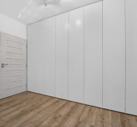 White built-in wardrobe in a family house with a wooden decor floor.