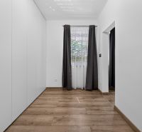 White room with wood-patterned flooring and a window, family house.