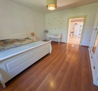 Bedroom in a family house with wood-patterned flooring, a bed, and a baby crib.