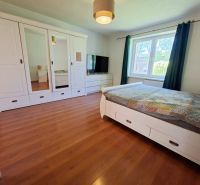 A bedroom in a family house with white furniture and a wooden decor floor.