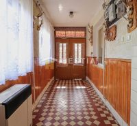 A hallway in a family house with a tiled floor and wooden wall paneling.