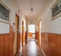 A hallway in a family house with wooden decor surfaces and patterned flooring.