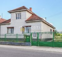 A family house in Borský Mikuláš with white walls and a green fence.