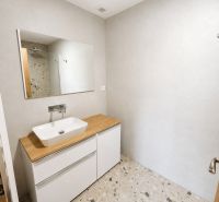 A bathroom with a terrazzo floor and wooden decor in a 2-room apartment.