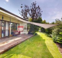 The family house in Hrubý Šúr has a wooden terrace and a landscaped garden with a lawn.