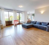 A spacious living room in a family house with a sofa, wooden floor decor, and a view outside.