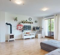 Living room in a family house with wood-patterned flooring and sliding doors.