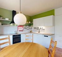 A kitchen in a family house with white cabinets, a green wall, and a round table.