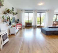 Living room in a family house with a fireplace, a large sofa, and a wooden-patterned floor.