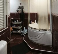 A bathroom with a bathtub, toilet, and storage shelves in a 2-room apartment.