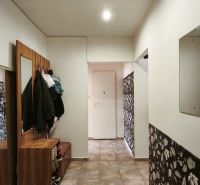 A hallway in a 2-room apartment with tiled flooring and floral patterned wallpaper.