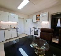 A kitchen in a family house with a light-colored kitchen unit, a ceramic hob, and a dining table.