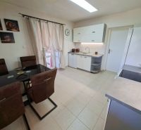 Kitchen with a dining table, kitchen unit, and paintings in a family house.