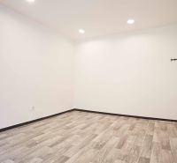An empty office interior with wood-patterned flooring and white walls.