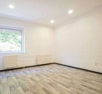 An office with a large window and a wooden decor floor.