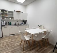A kitchenette in commercial premises with white furniture and a wooden decor floor.