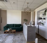 Commercial premises with a wood-patterned floor, a reception desk, and a green sofa.