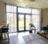 Commercial space with a green sofa, table, and wooden decor flooring.