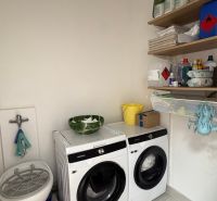 Washing machine and dryer in commercial premises with supplies on shelves.
