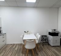 A kitchen corner with white furniture, a table, chairs, and a wooden decor floor.