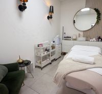 Treatment room with a bed, chair, and cosmetic products in commercial premises.