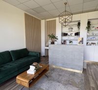 Commercial space with a sofa, reception, shelves, and a floor with wooden decor.