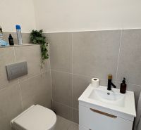 Bathroom with toilet and sink, light tiles, commercial spaces.