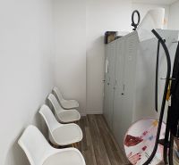 Interior of commercial space with white chairs and cabinets, floor with wooden decor.