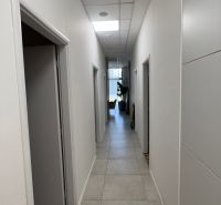 A narrow corridor with light tiles and multiple doors in commercial premises.