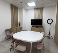 Business premises with a conference table, folding chairs, and a television on the wall.