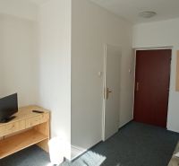 A hotel room with a television on the table and a door.
