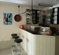 A bar counter and bar stools in an accommodation facility with glasses on the shelves.