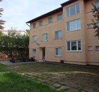The exterior of the hotel and guesthouse buildings in Patince with a grassy area and a fireplace.