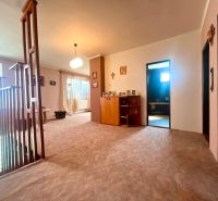 A hallway in a family house with wooden glass railings, decorations, and an entrance to the bathroom.