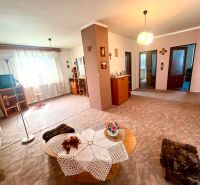 Living room in a family house with furniture, decorations, and a TV on a wooden floor.