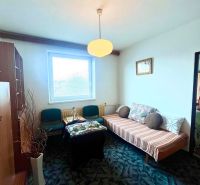 A room in a family house with a carpet, a sofa, and a table under a pendant light.