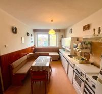A kitchen in a family house with a corner sofa and a floor with a wooden decor.