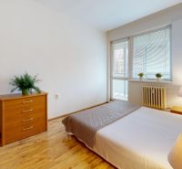 Cozy bedroom in a 2-room apartment on K výstavisku street with a wooden dresser and bed.