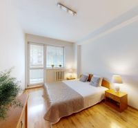 A bright bedroom with a large window and a bed in a 2-room apartment on K výstavisku street.