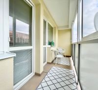 A glazed balcony of a 2-room apartment on K výstavisku street with comfortable armchairs and carpets.
