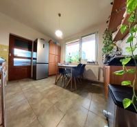 A kitchen with a table and chairs, a refrigerator, a cabinet, and plants in a 4-room apartment.