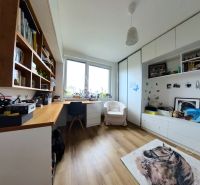 A study in a 4-room apartment with a wooden decor floor, shelves, and an armchair under the window.