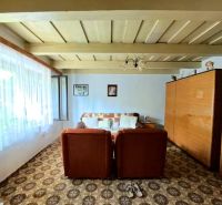 A living room in a family house with brown furniture and a patterned carpet.