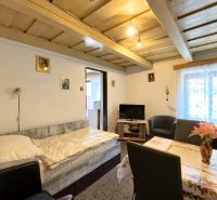 Living room in a family house with a wooden ceiling, seating, and a television.