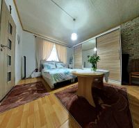 A bedroom in a family house with a wooden decor floor, flowers on the table, and a bed.