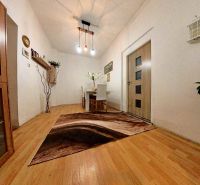Interior of a family house with a wooden decor floor, a table, and decorative lighting.