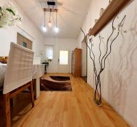 Interior of a family house with a dining table, wood-patterned flooring, and pendant lamps.