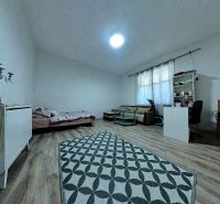 A room in a family house with a wooden decor floor, a bed, and a desk.